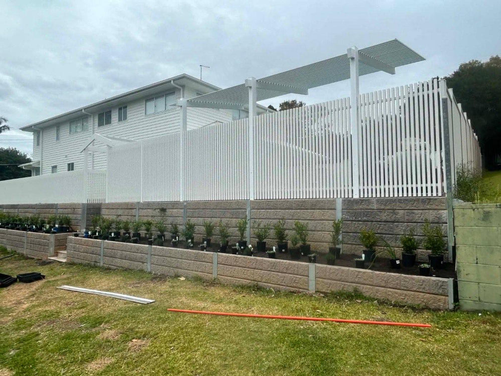 Tiered concrete block retaining walls with new garden beds and white slat fence
