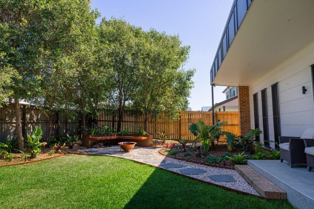 Backyard with curved garden beds, stepping stones and new turf