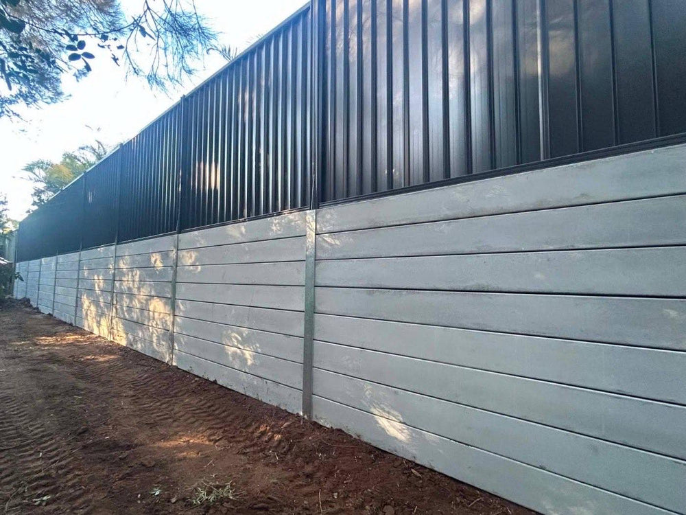 Concrete sleeper retaining wall with black Colorbond fence