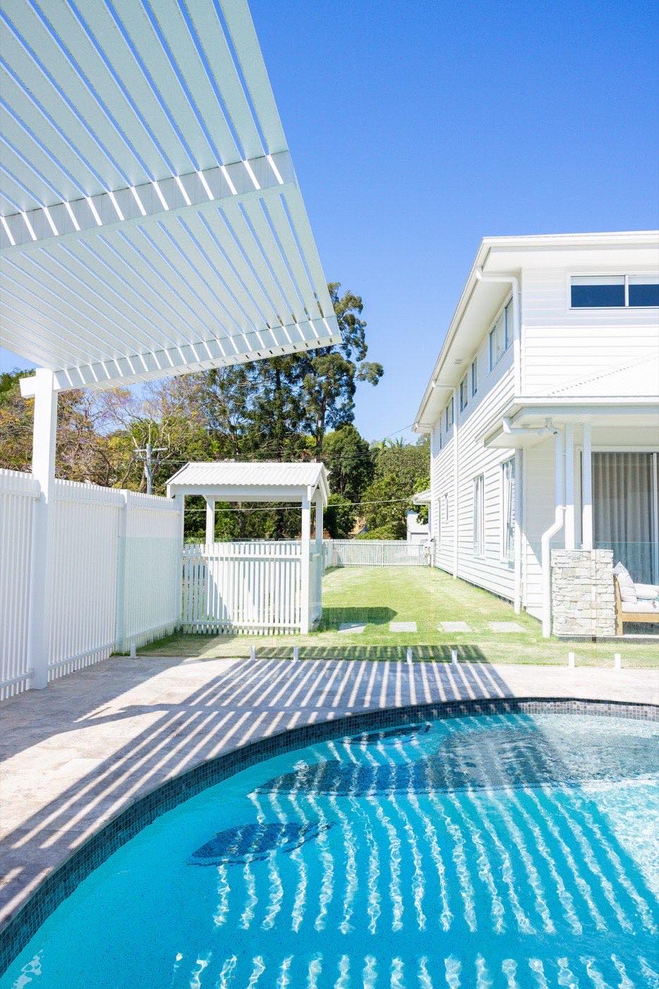 Pool fence and gate beside a white weatherboard home
