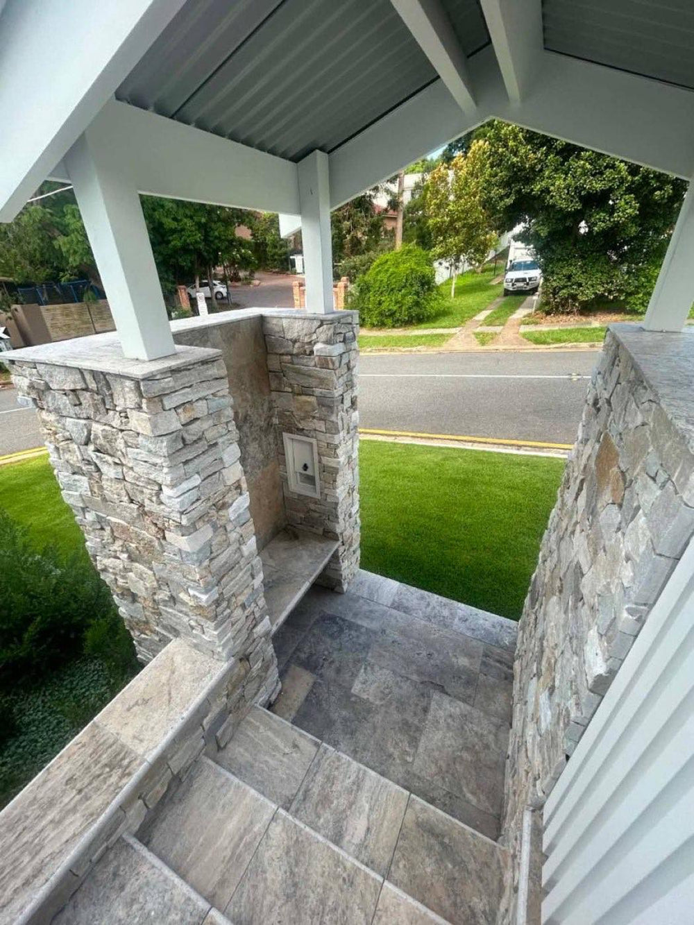Stacked stone entry pillars with travertine steps and new turf