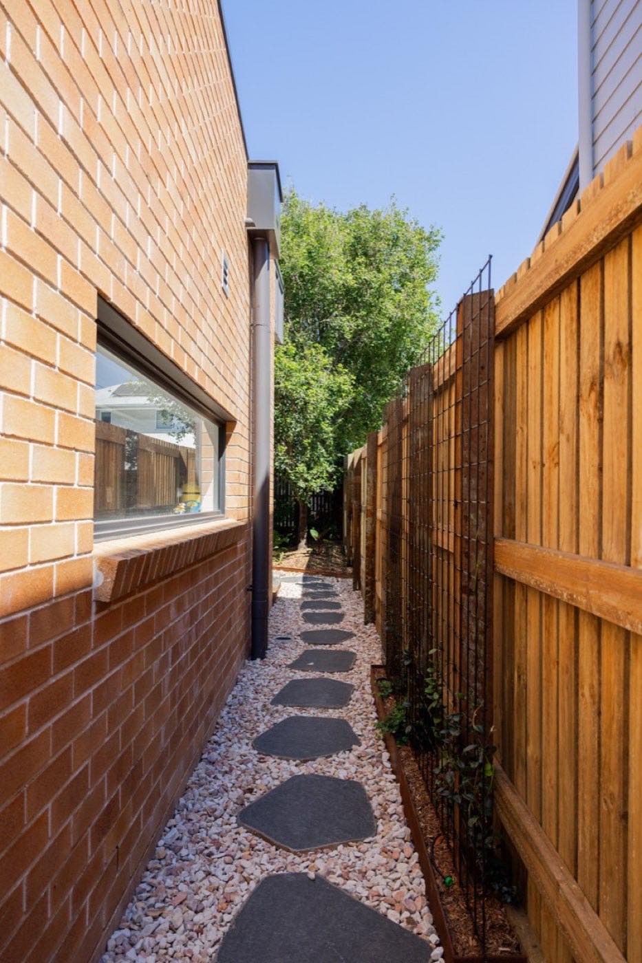 Timber paling fence and stepping stone path down a brick side yard